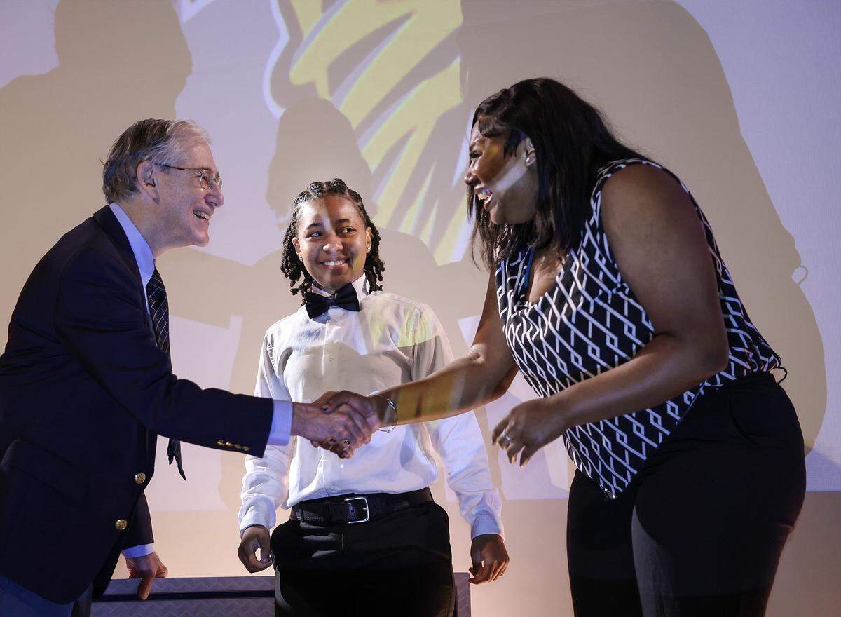 William Thompson, left, president of the Florida Prepaid College Foundation, shakes hands with Patricia Smith as Yaz'Nique Jean Francois looks on. Both students received scholarships during the Booker T. Washington Senior High School Class of 2026 Senior Awards Ceremony, Tuesday, May 19, 2026, in Miami, Florida.