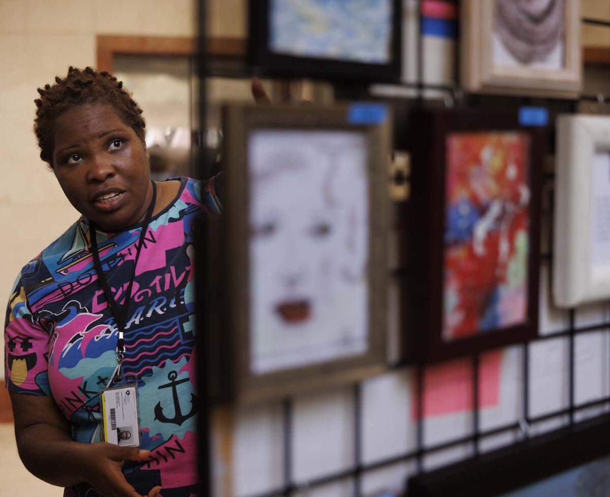 Patricia Battles points on her artwork during the Camillus House art show on Wednesday, May 27, 2026, in the foyer at Amerant Bank in Coral Gables, Fla. “Art allows me to not overthink and let things flow, its treatment, we're given tools to heal and become better people as a way of healing,” said Battles.
