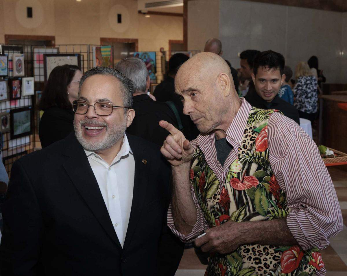 David Rohn, Camillus art therapy instructor, right, points out artists work to Robert E Herrera, CFO of Camillus House,   during the Camillus House art show on Wednesday, May 27, 2026, in the foyer at Amerant Bank in Coral Gables, Fla.“I never could have imagined how powerful the practice of self expression can be for them, and they're all so mutually so supportive. They sit down and engage with their own self on a different level with the people around them,” said Rohn. 