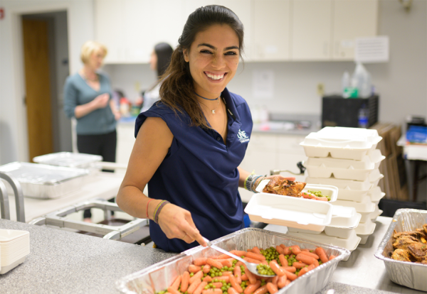 Woman scooping food onto platter. 