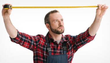 A man in a red plaid shirt and overalls holds a yellow measuring tape, stretching it out horizontally with both hands against a white background.