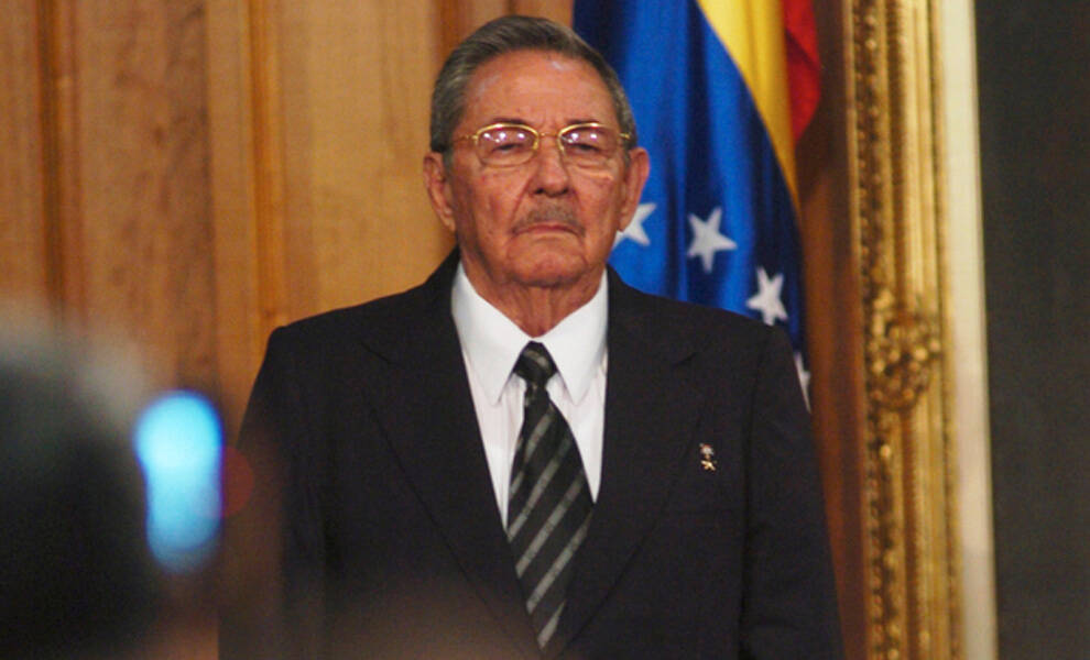 Former Cuban President Raul Castro wearing a dark suit flag during a formal government or diplomatic event.
