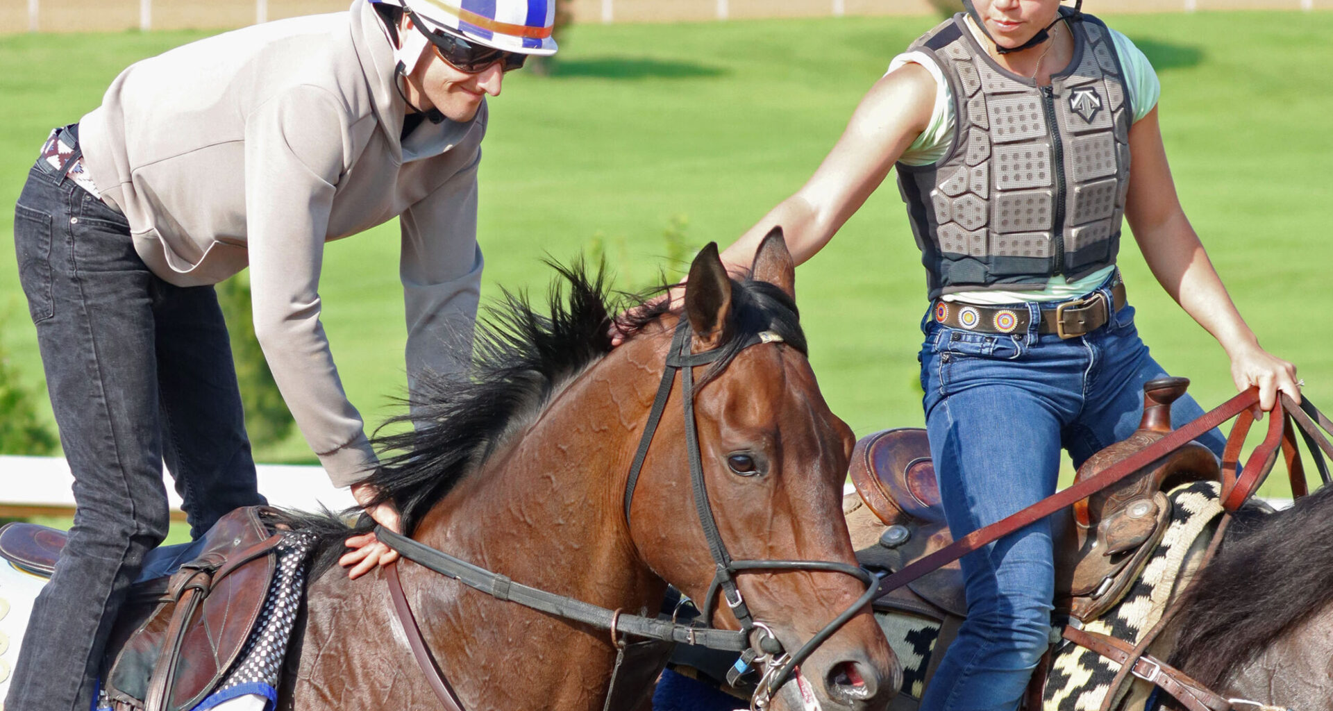 Closely cropped photo of Redland Rebels being ponied during a morning exercise. The person ponying Redland Rebels reaches over to pet him behind his ears from her horse, while his exercise rider smiles. (Photo: ©Cady Coulardot / Coady Media)