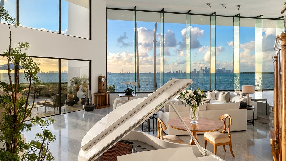 Luxury living room with grand piano and large glass windows overlooking Biscayne Bay
