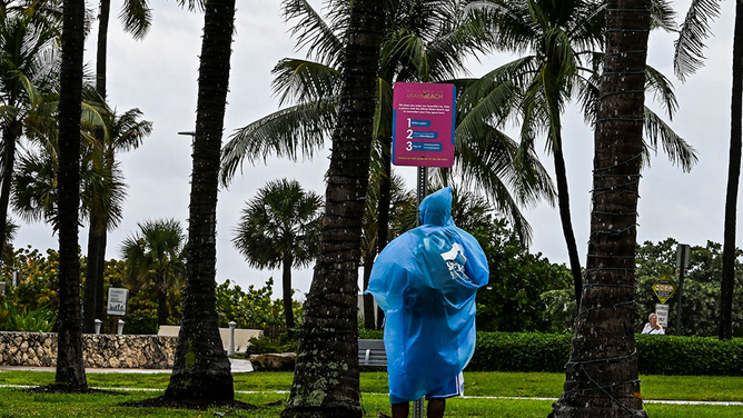 FILE - People wear rain covers as they walk in the park during heavy rain in Miami Beach, Florida, on April 12, 2023.