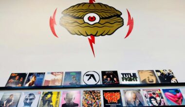 Photo of a wall with a shell-shaped logo and vinyl records.
