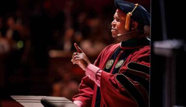 A man in traditional academic cap and gown delivers a speech at a commencement ceremony.