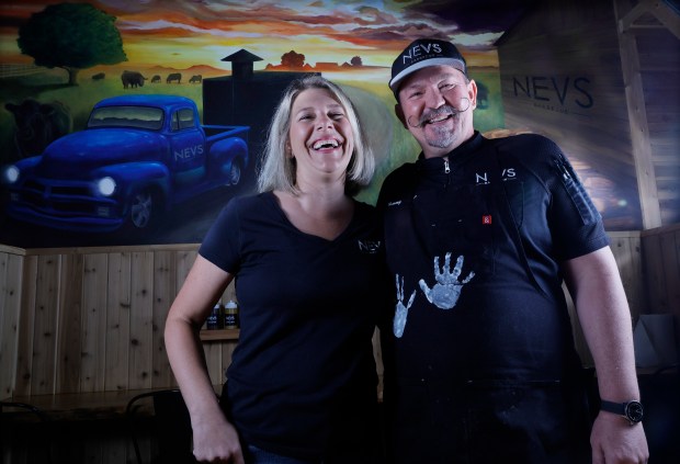 Kelsey and Tommy Nevill, owners of NEVS Barbecue in Palm Beach Gardens, are seen in front of the dining room mural on Thursday, May 7, 2026. The restaurant was featured recently on "Diners, Drive-Ins and Dives." (Joe Cavaretta/South Florida Sun Sentinel)