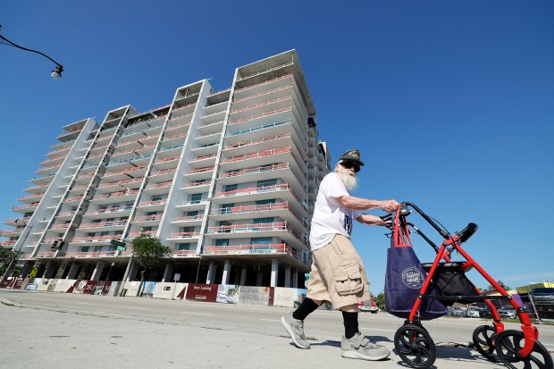 A man on Friday walks past 21 Hollywood, a 13-story apartment building going up on the west side of Federal Highway a few blocks south of Sheridan Street. (Amy Beth Bennett/South Florida Sun Sentinel)