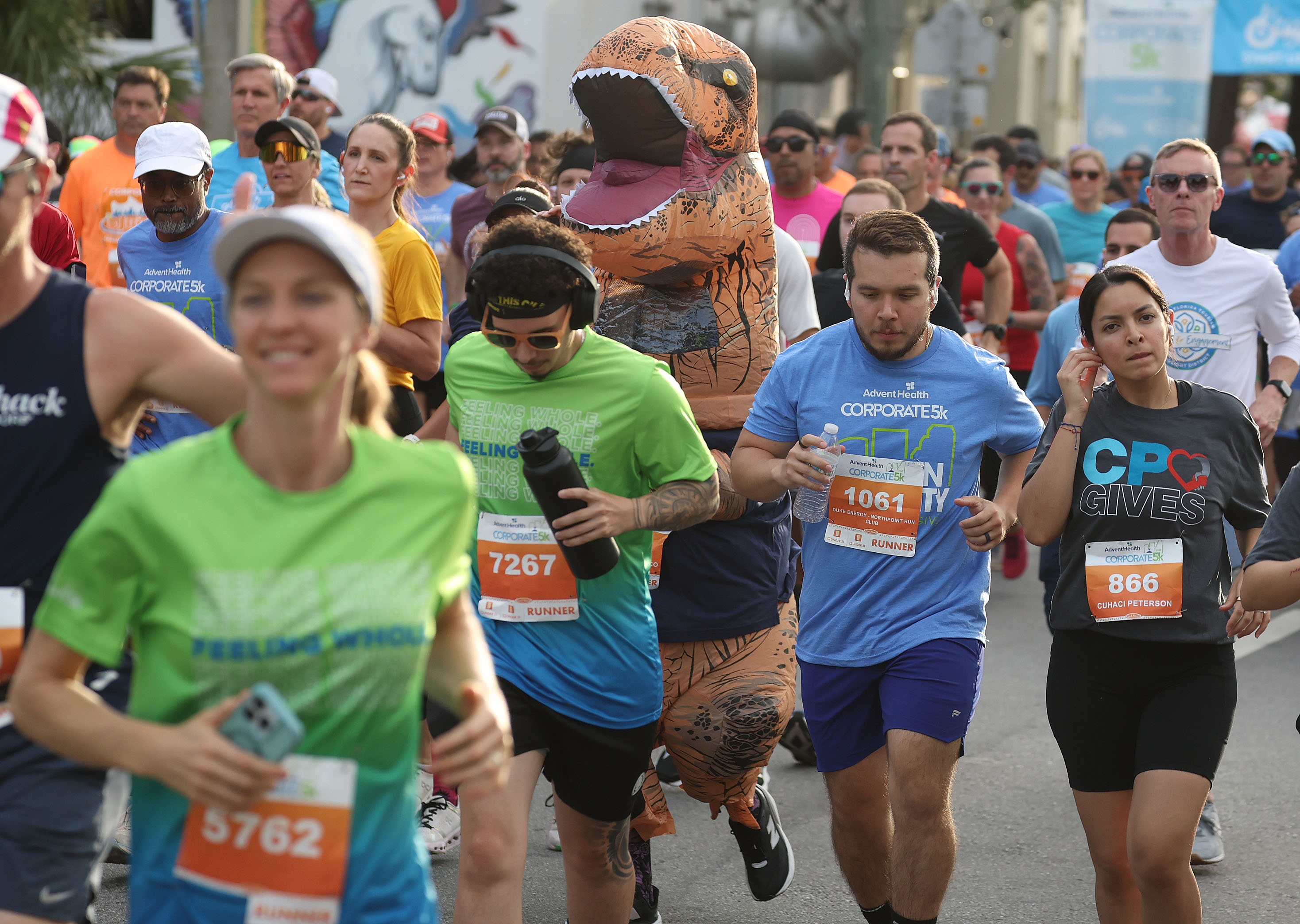 A runner in a dinosaur costume joins others during the...