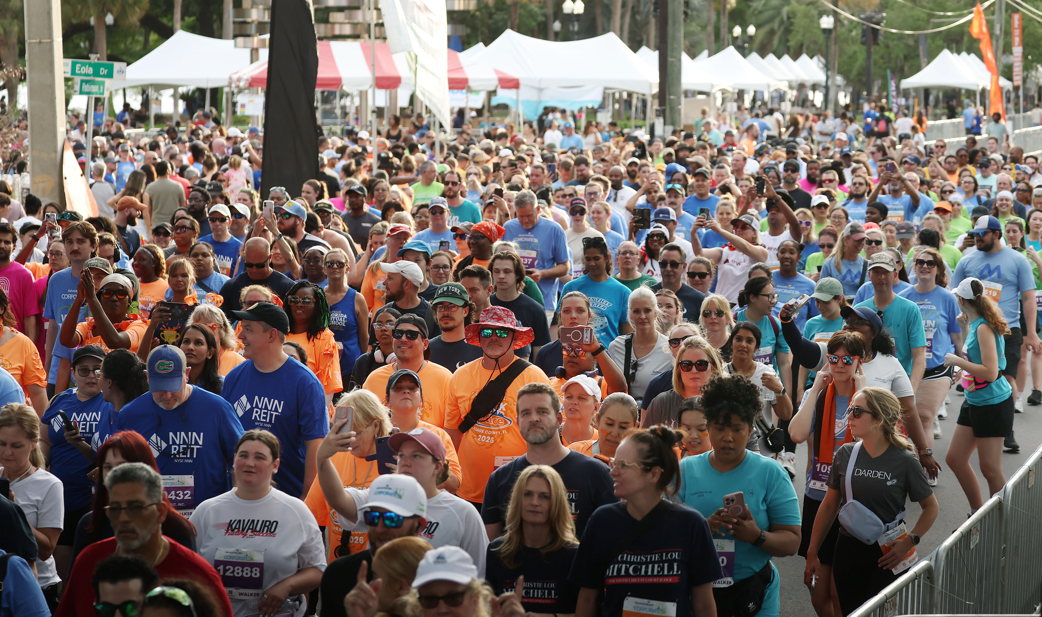 Runners and walkers crowd together as they cross the starting...