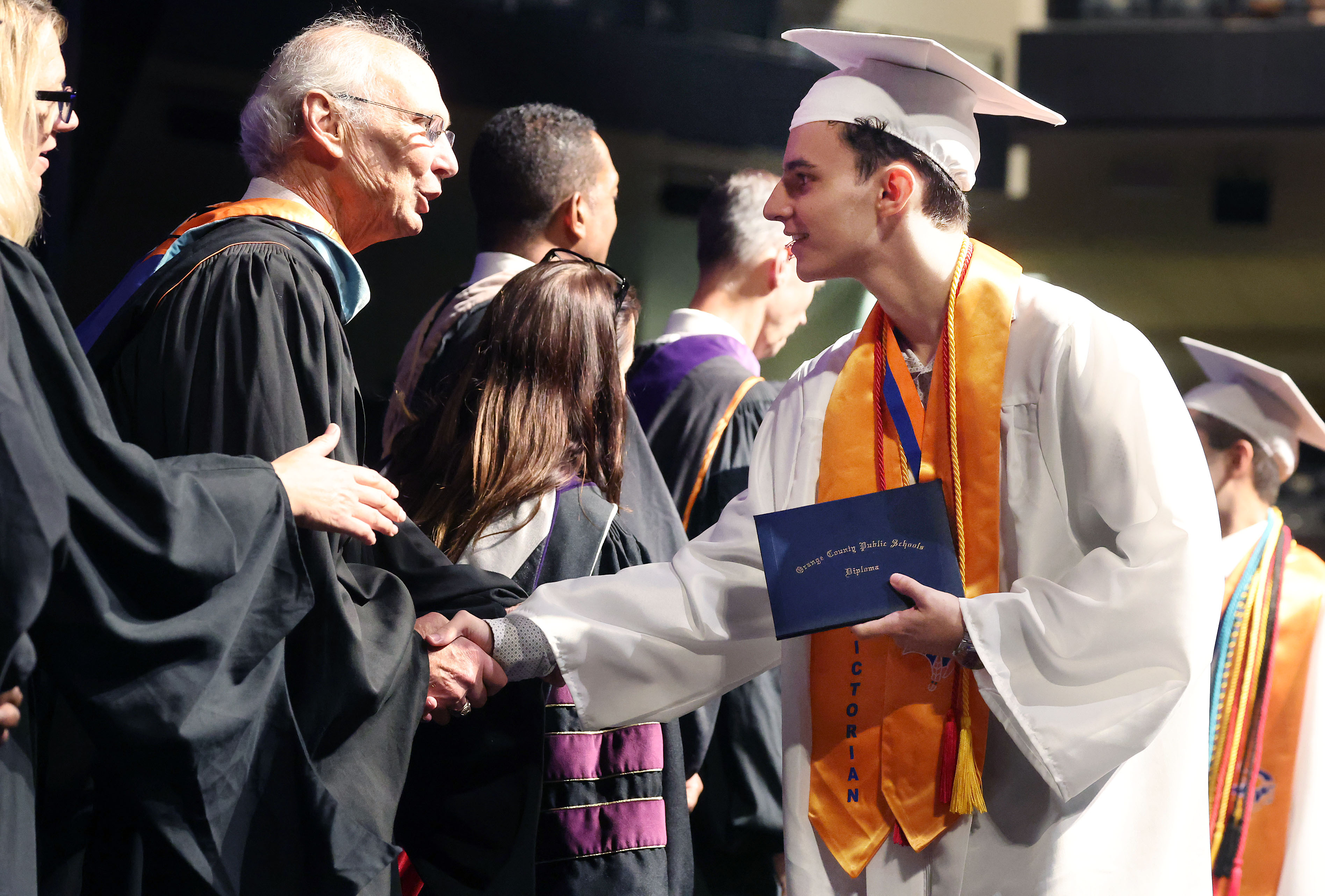 Valedictorian Lucca Carvalho Magalhaes shakes hands after receiving his diploma...