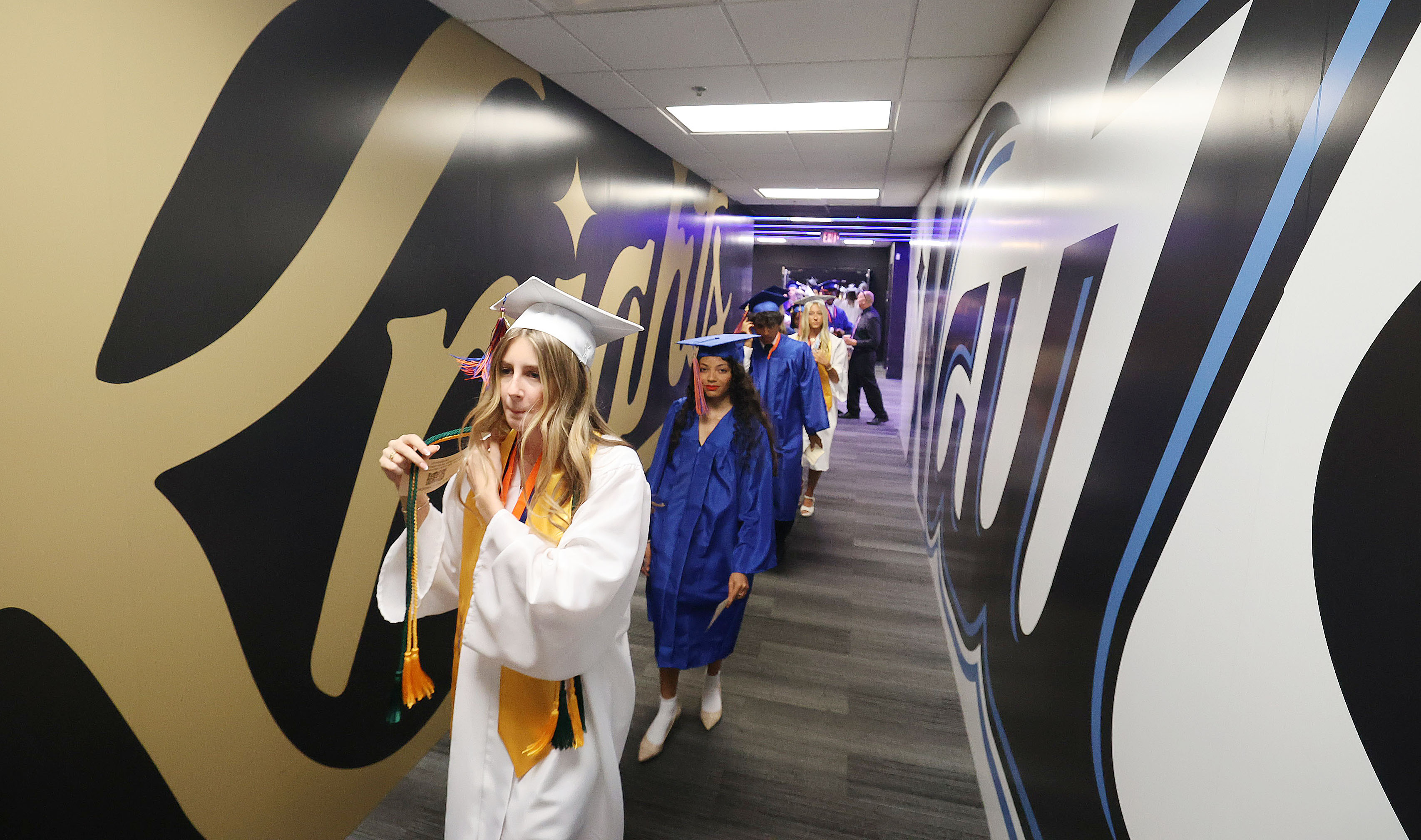 Graduates walk down a tunnel leading into the arena during...