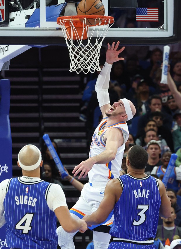 Thunder guard Alex Caruso (top) scores during the Oklahoma Thunder at Orlando Magic NBA game at the Kia Center in Orlando on Tuesday, March 17, 2026. Oklahoma City won the game 113-108. (Stephen M. Dowell/Orlando Sentinel)