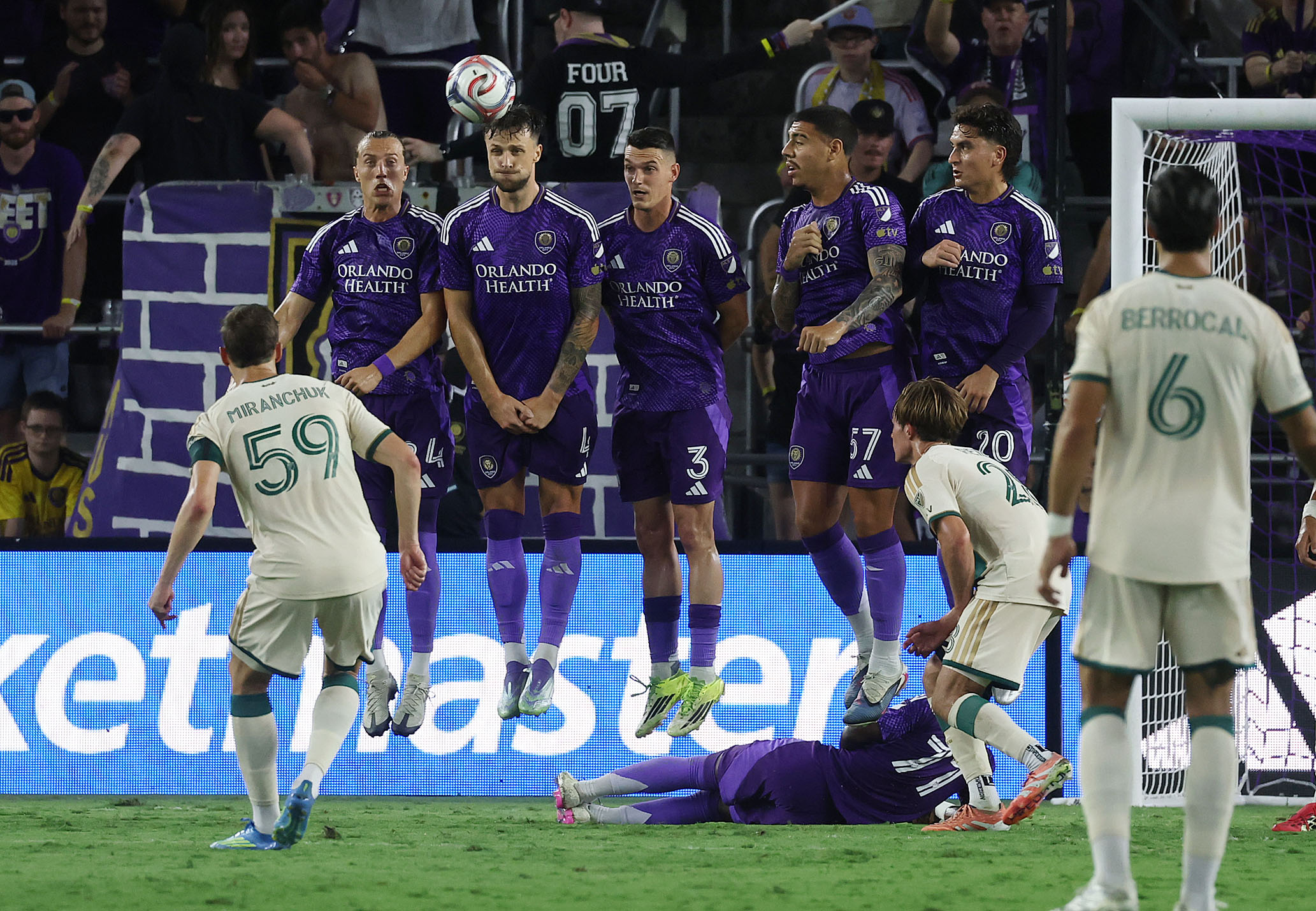 Orlando players leap to try to stop a kick during...