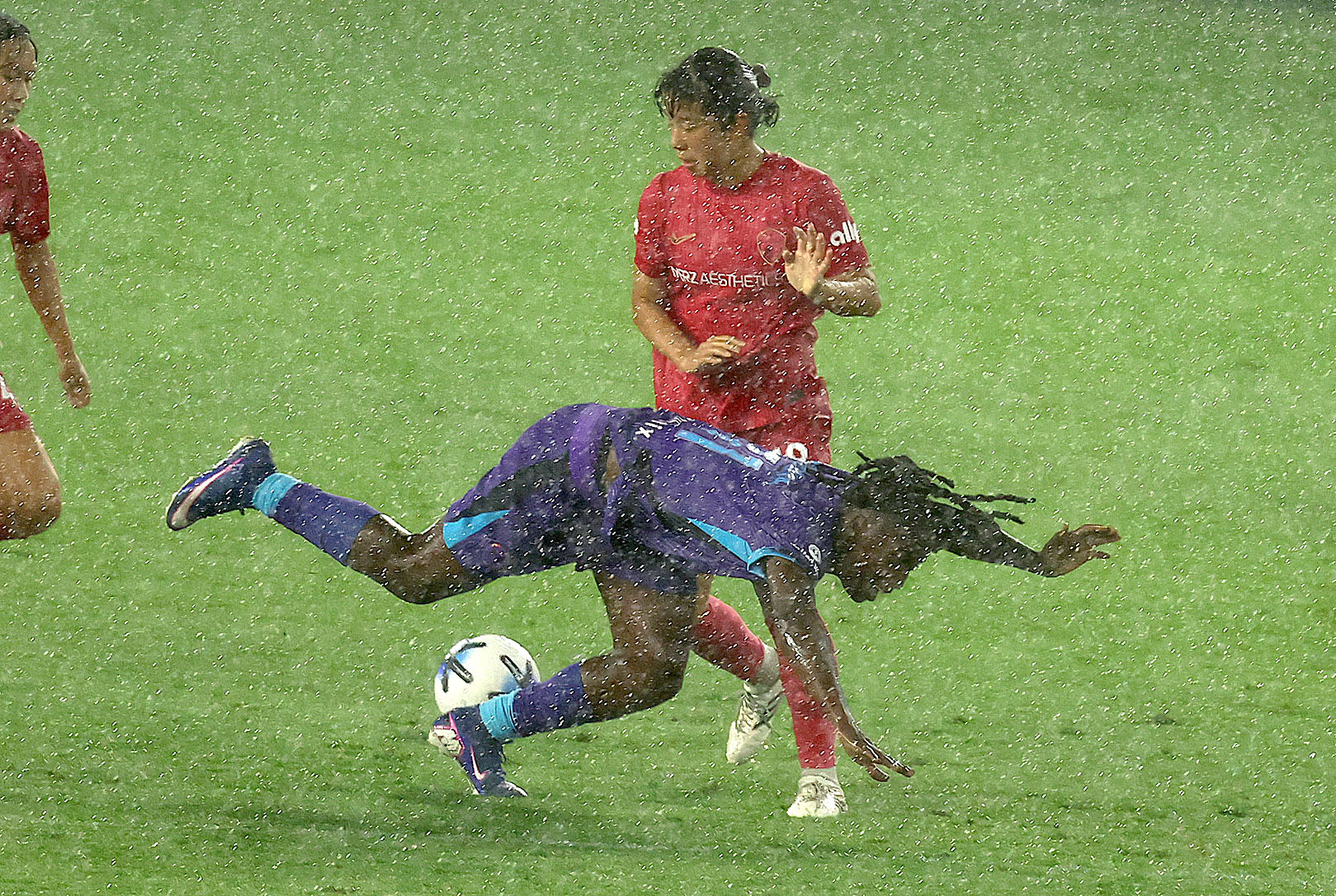 Orlando player Barbra Banda (bottom) falls in the pouring rain...