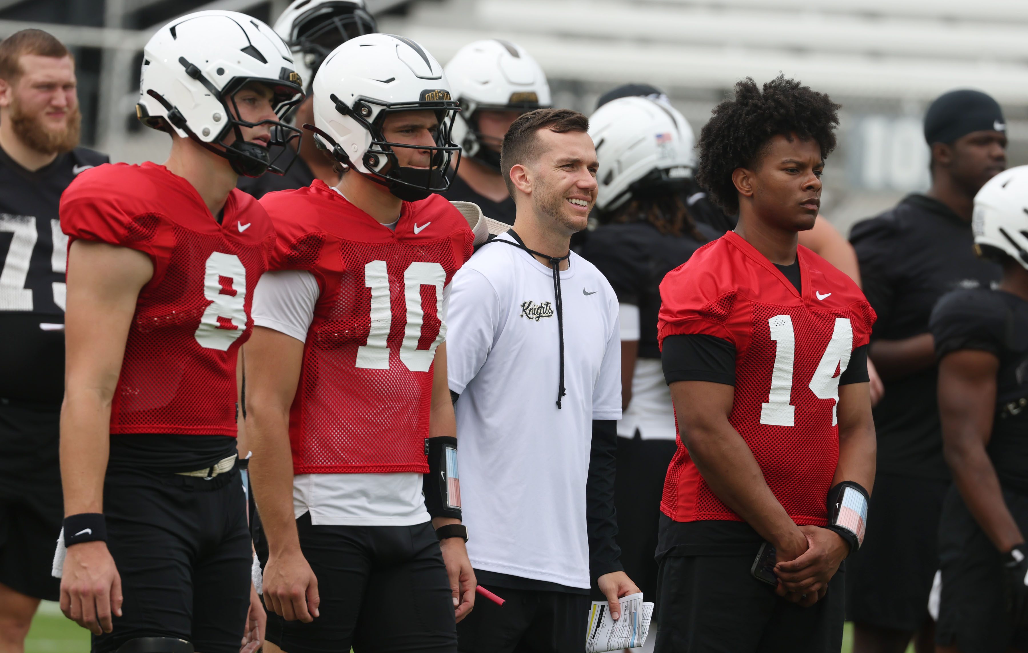 UCF quarterbacks coach McKenzie Milton (white shirt) is pictured with quarterbacks Rocco Marriott (8), Kaleb Annett (10), and Alonza Barnett III (14) during UCF football pPractice at the Acrisure Bounce House Stadium Saturday in Orlando. (Stephen M. Dowell/Orlando Sentinel)