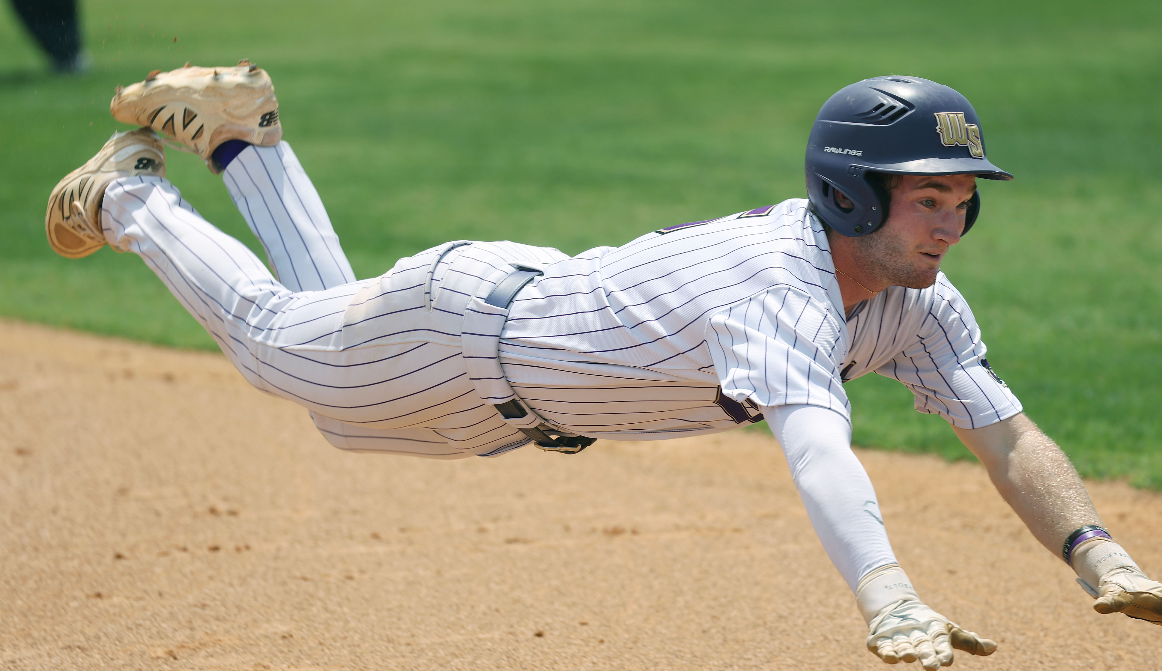 Winter Springs High baseball player Brandon Curl slides into third...