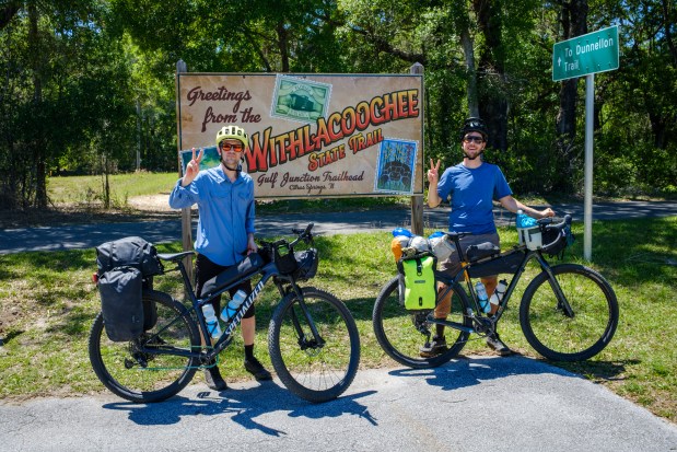 Patrick Connolly and Evan Sanders stop for a photo op in front of a Withlacoochee State Trail sign while riding the Huracan bikepacking route on April 15, 2026. (Patrick Connolly/Orlando Sentinel)