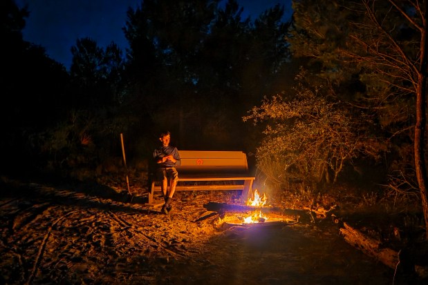 Evan Sanders enjoys a campfire at Sawgrass Fill camp on April 17, 2026. (Patrick Connolly/Orlando Sentinel)