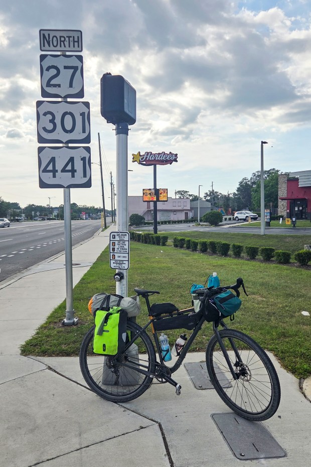 Patrick Connolly and Evan Sanders stop to cross U.S. Route 441 in Belleview during a bikepacking trip on April 18, 2026. (Patrick Connolly/Orlando Sentinel)