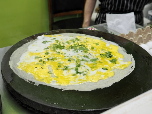 Each thin crepe is spread on a griddle. An egg is cracked on top and spread over the surface. The jianbing at TT Crepes are made fresh to order. (Photo courtesy Lisa Wilk/TasteCookSip.com)