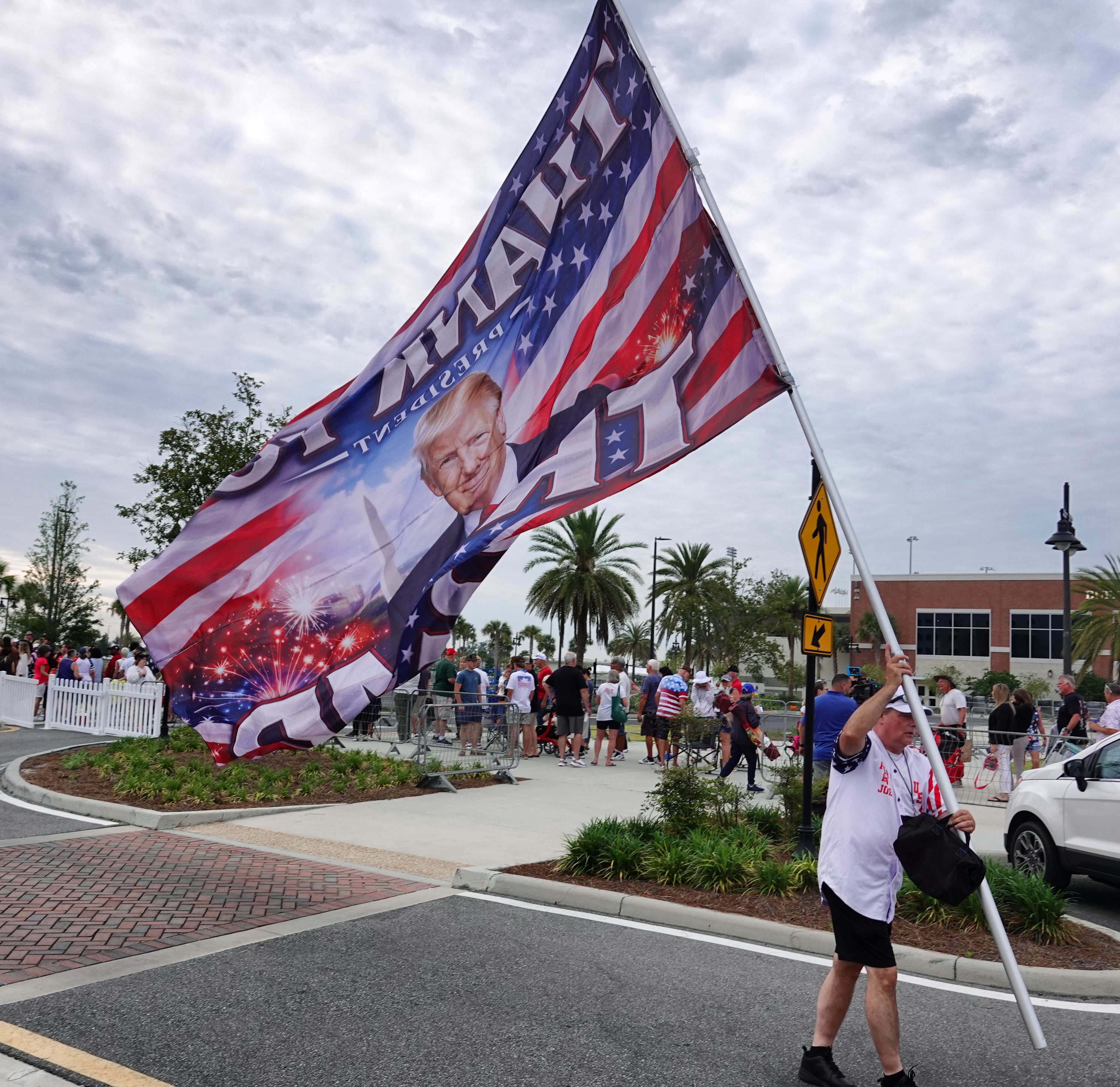 A flag-toting fan of President Donald Trump welcomes supporters while...