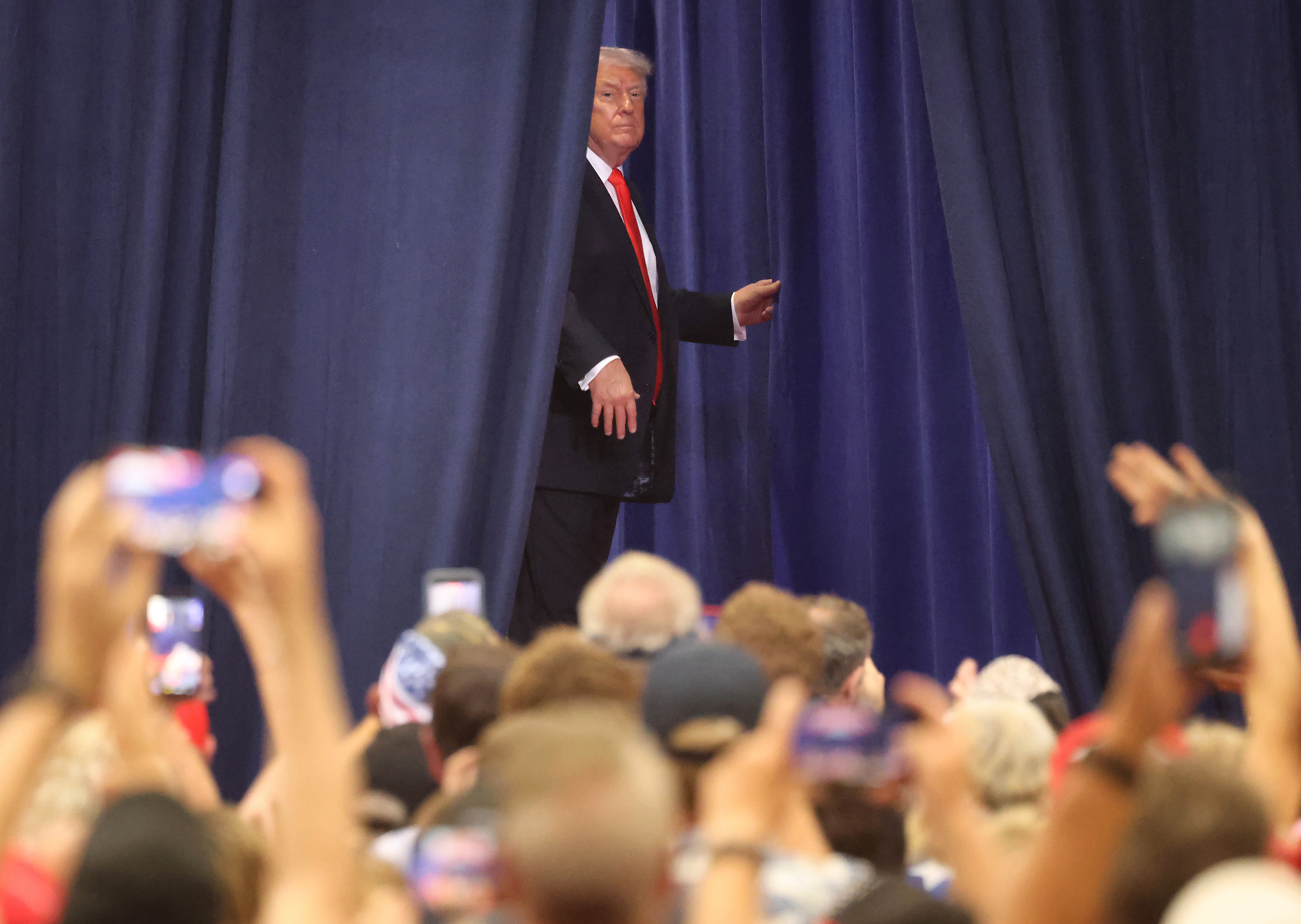 President Donald Trump glances back at the cheering crowd as...