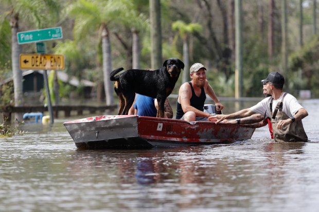 Residents ride in a boat in a neighborhood inundated by historic flooding of the Alafia River caused by Hurricane Milton in 2024. The county could divert funds set aside for natural disasters to the Rays stadium. (Luis Santana/Tampa Bay Times)