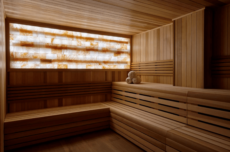 photo of a sauna with wooden walls and tinted windows and three towels