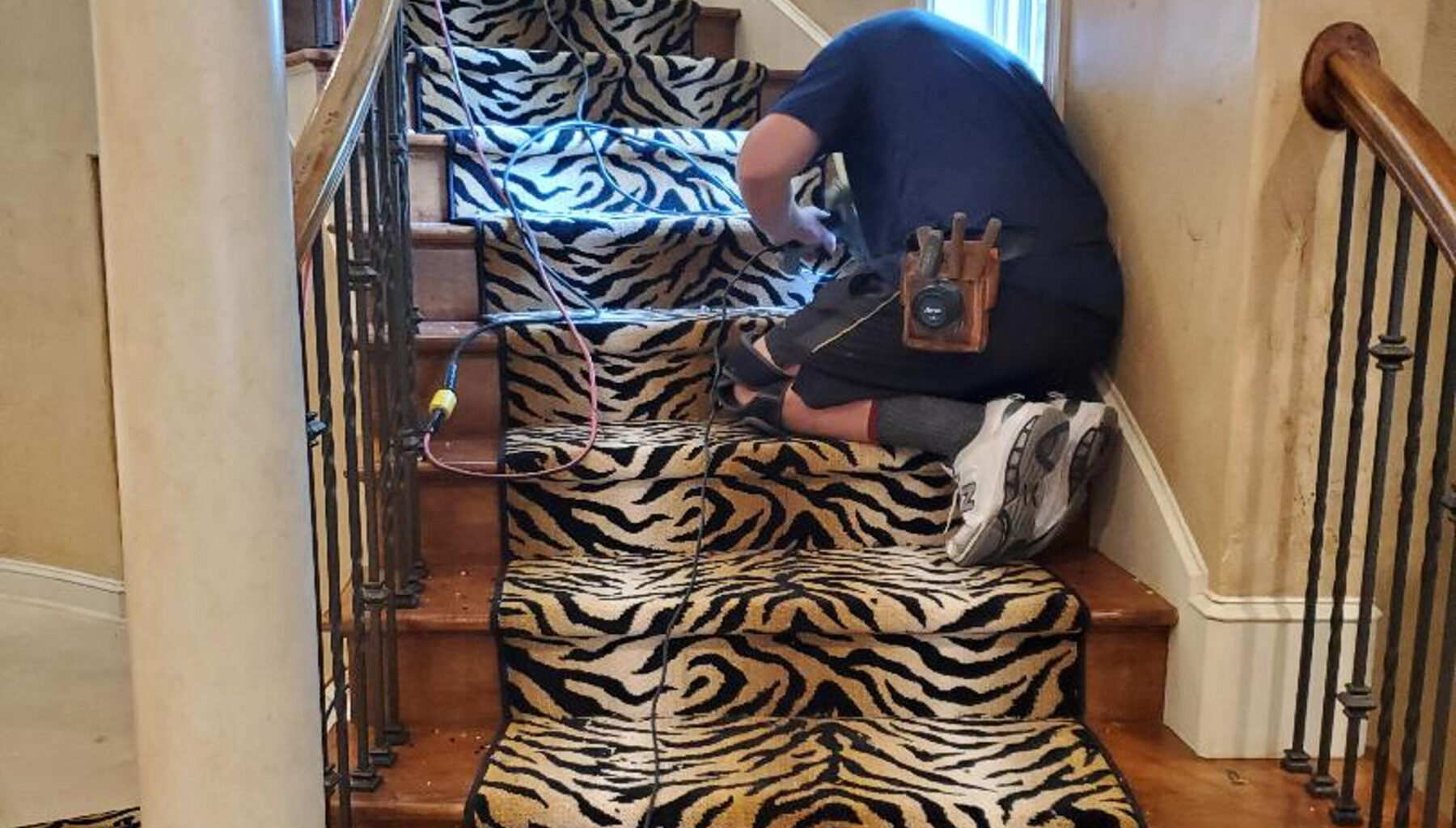Mark Stone installing tiger pattern accent down staircase center.