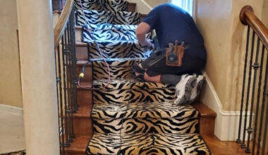 Mark Stone installing tiger pattern accent down staircase center.