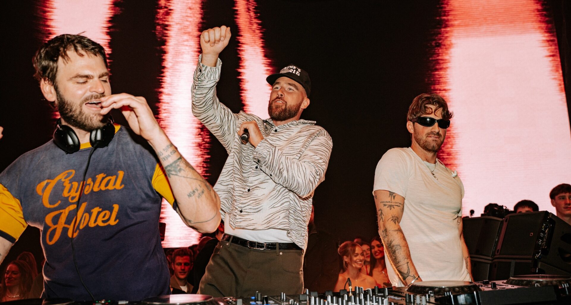 Photo of Travis Kelce and Chainsmokers behind the decks dancing.