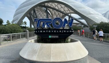 TRON Lightcycle Run sign in front of a sleek, glowing dome, echoing Tomorrowland&rsquo;s energy at Disney Parks, similar to TRON: Ares.