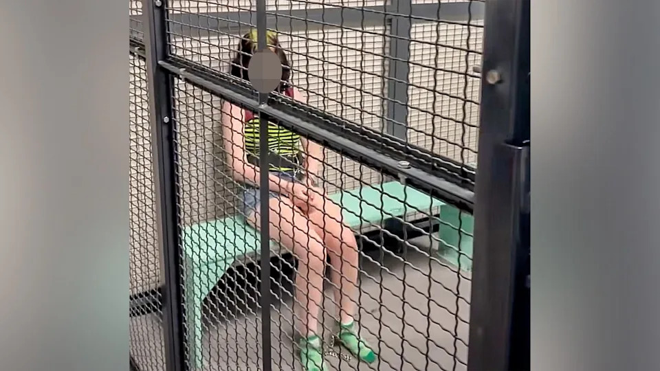 Interior view of a jail cell with metal bars and a bench