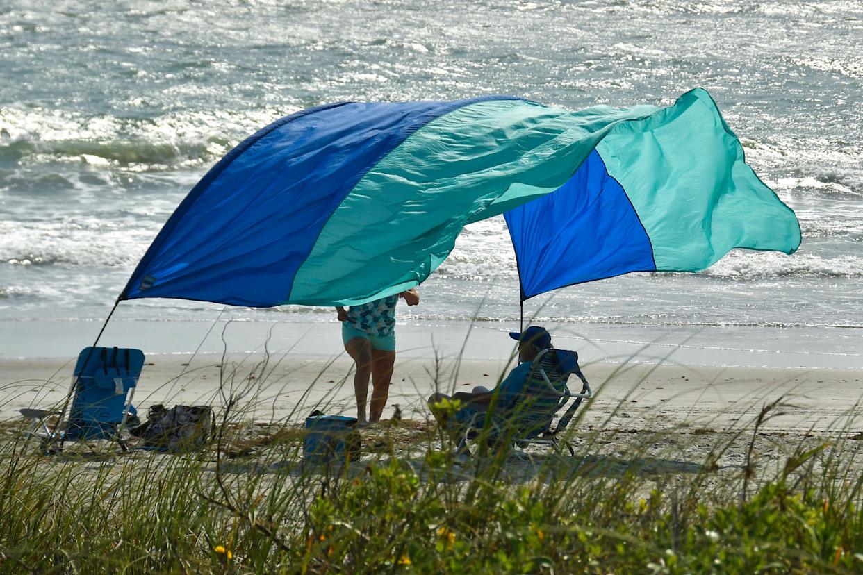 Photo shows a beachgoers sun canopy flapping in the strong winds at Tables Beach (Tim Shortt / Florida Today via USA Today Network)