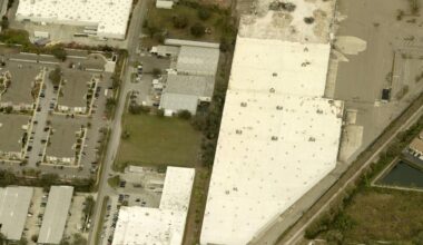 Aerial view of a vacant industrial lot at the corner of S Lois Avenue and W Pearl Avenue in Tampa, surrounded by warehouses and apartment complexes.