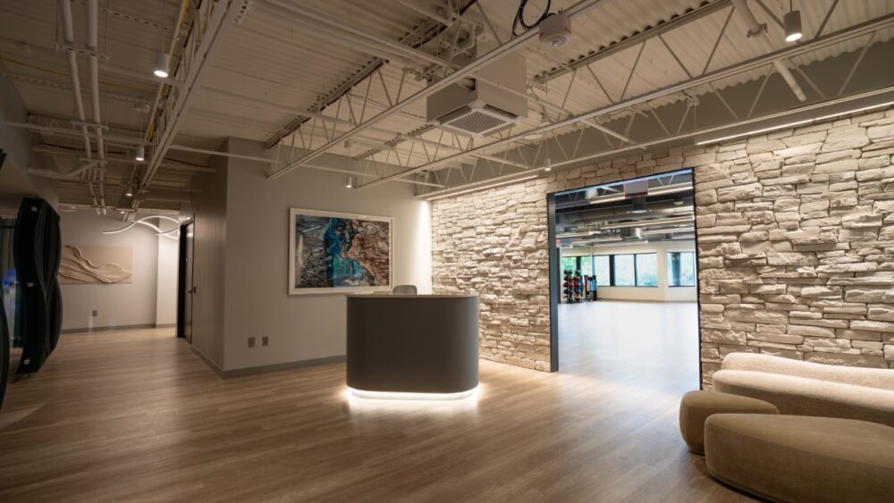 Reception area inside Power Design wellness center with stone wall and fitness studio entrance