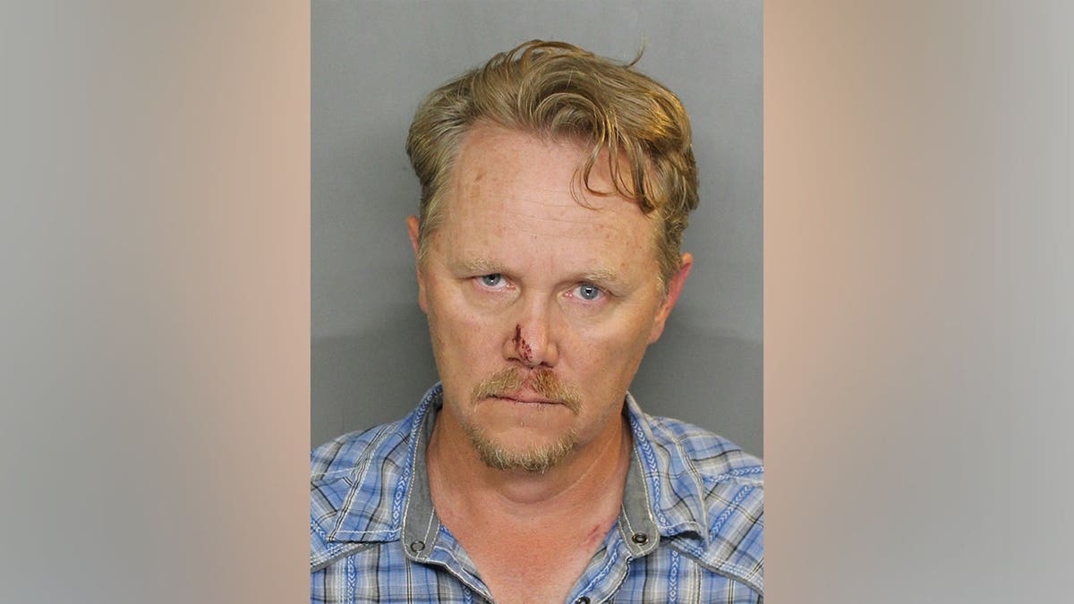 Dennis Lee Olson standing in a mugshot photo