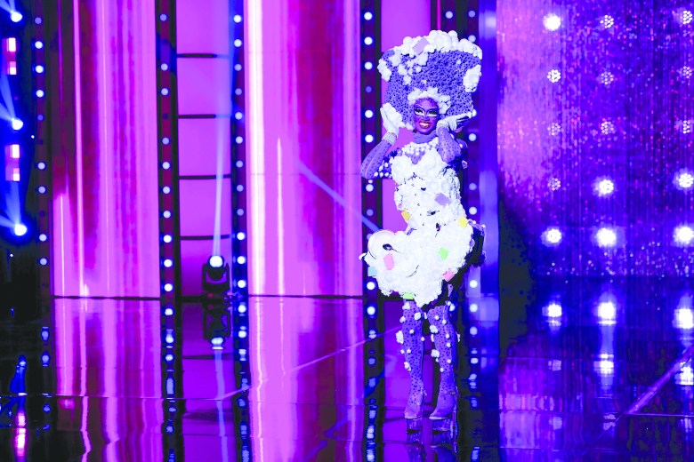 A shot from 'RuPaul's Drag Race' Season 17 of Lucky Starzzz in a purple soapy sponge costume with dishes and utensils.