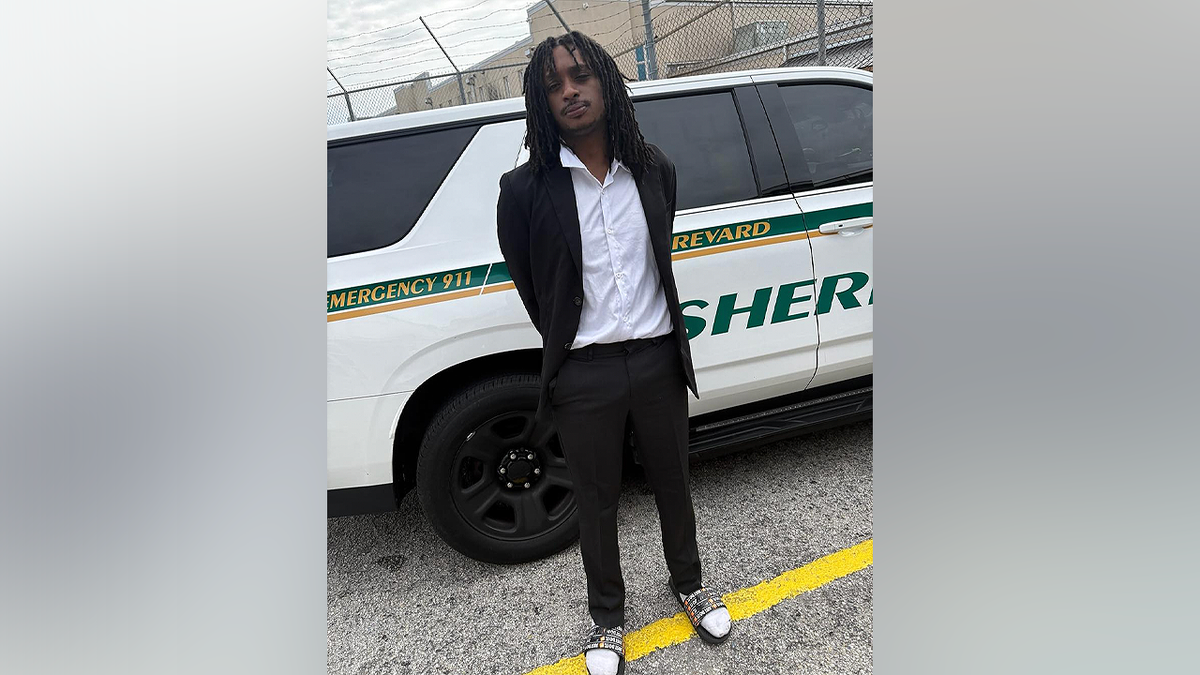 Christopher Jones stands in a suit and slide sandals after being arrested for allegedly driving over 100 mph in Brevard County, Florida