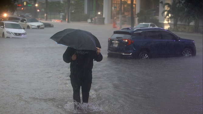 A pedestrian walks through a flooded street caused by a deluge of rain from a tropical rain storm passing through the area on June 4, 2022 in Miami, Florida.