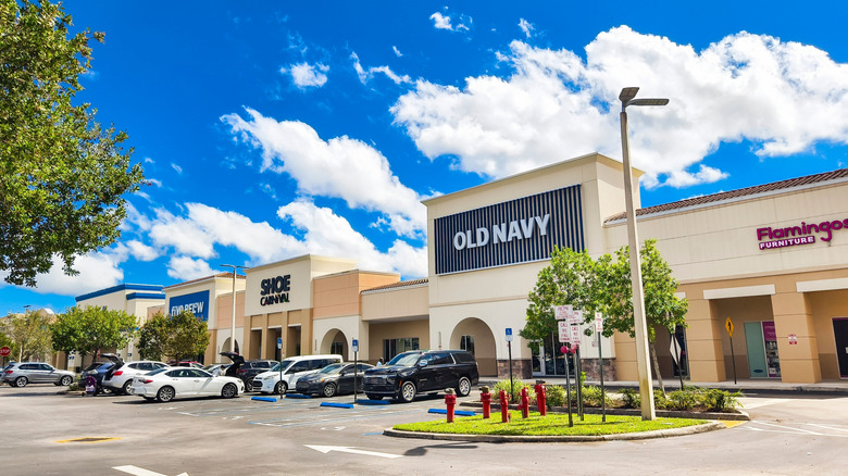Exterior of Gardens Promenade shopping center, with cars parked in front of stores