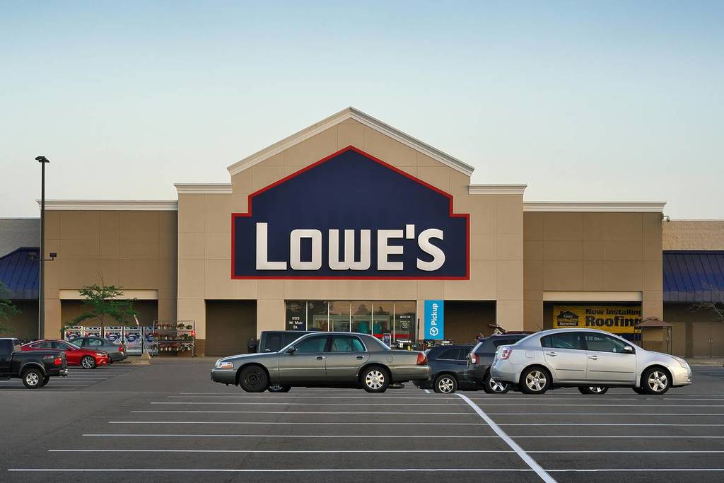 Front view of a Lowe's store entrance with parked cars in the lot during the day