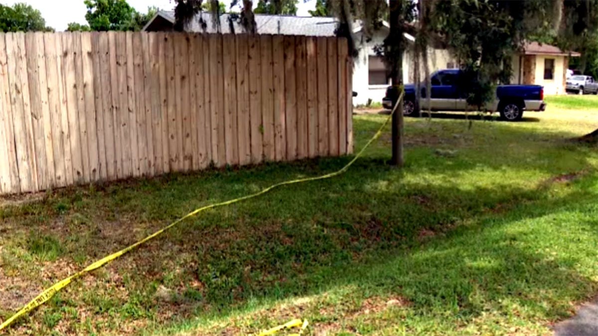 crime scene tape near a tree and wood fence