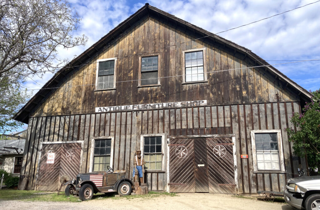 Weathered boards and hand-hewn doors tell a quieter chapter of Jacksonville’s past at the Antique Furniture Shop — also known as the B. and B. Barn — where the town’s early milling trades once helped shape a gold rush community better known for its brick-lined streets. Photo: Jim Flint.