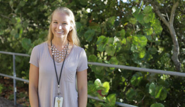 portrait of a lady in a purple shirt and fancy necklace standing in front of mangroves
