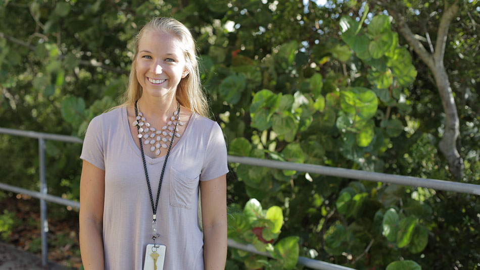 portrait of a lady in a purple shirt and fancy necklace standing in front of mangroves