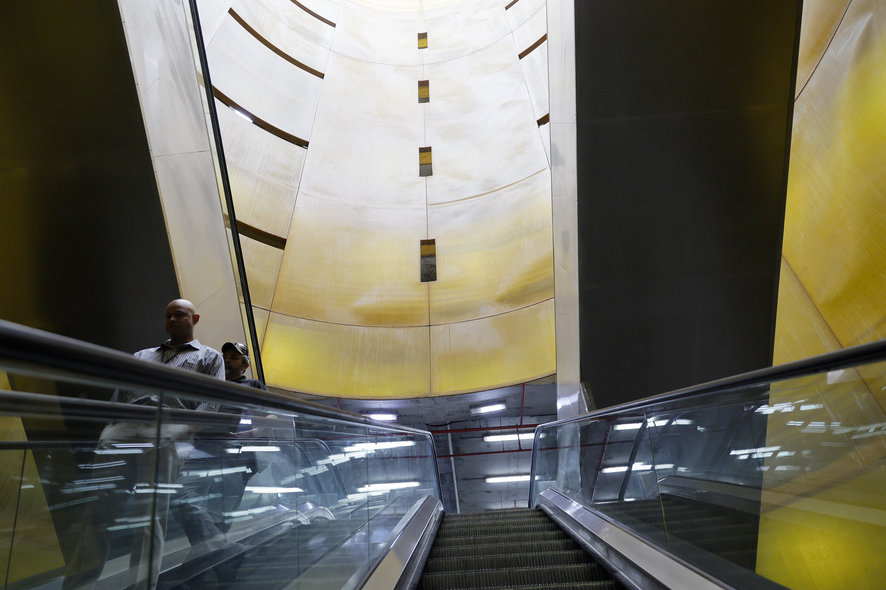 Travelers ride an escalator inside of âLight Cylinders,â by Jody...