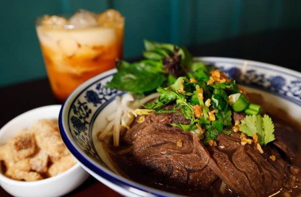 Sliced Beef Shank Boat Noodles "A rich, aromatic Thai noodle dish with dark flavorful broth, tender meats, and meatballs. Served with Chinese broccoli, bean sprouts, fried garlic, cilantro, scallions, and pork rinds" with with Thai Tea Thai dishes at Noods, at Thai restaurant in MetroWest, on Monday, May 11, 2026. (Ricardo Ramirez Buxeda/ Orlando Sentinel)